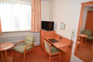 a room with a desk with a television and chairs at Zweibettzimmer-08-OG in Borkum