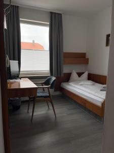 a bedroom with a bed and a desk and a window at Budget-Einzelzimmer-06-EG in Borkum
