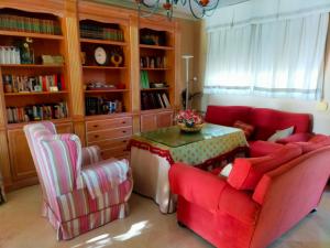 ein Wohnzimmer mit einem roten Sofa und zwei Stühlen in der Unterkunft Precioso chalet próximo a Sevilla con jardín y piscina privada 8 personas Wifi gratis 2 salones 4 dormitorios 2 baños in Consolación