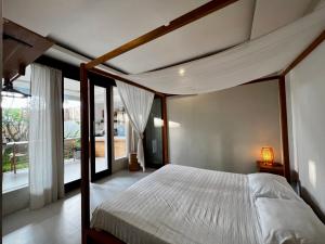 a bedroom with a canopy bed and a balcony at Base Villa in Canggu