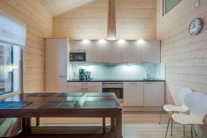 a kitchen with white cabinets and a wooden wall at Rukankarhu Apartment in Ruka