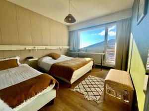 ein Hotelzimmer mit zwei Betten und einem großen Fenster in der Unterkunft Hotel Perdrix in Super Besse