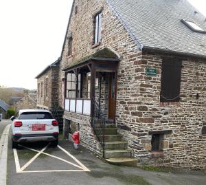 a car parked in front of a brick building at "La chambre des TISSERANDS" in Ménil-Hubert-sur-Orne
