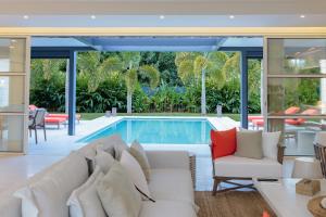 a living room with a white couch and a swimming pool at Hill Rock villas - Rouge Corail in Petit-Bourg