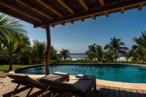 a swimming pool with two lounge chairs and the ocean at Lu Iba in Tlachicón