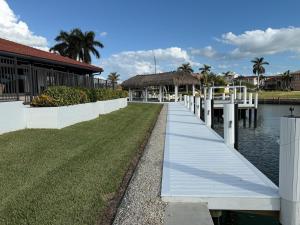 a dock in front of a building next to a body of water at Waterfront Tip Lot Treasure w/ Southern Sunshine in Henry Key