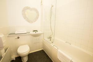 a bathroom with a toilet and a tub and a sink at Gray Manor Hotel in Andover +34 photos