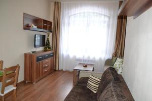 a living room with a couch and a tv and a window at Apartment 7 Donovaly, AD Kamzík in Donovaly