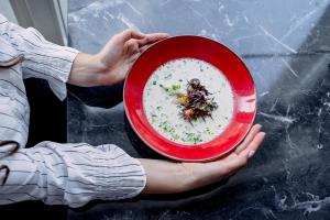 a person holding a red plate with insects on it at Hotel Lamberton in Ołtarzew