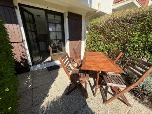 a wooden table and two chairs in front of a house at Le Refuge Marin in Courseulles-sur-Mer