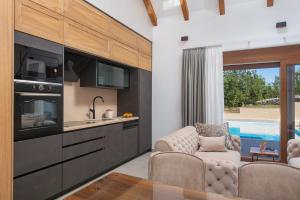 a kitchen with a living room with a couch and a sink at Unique Villa Pietra with heated private pool in Šestanovac