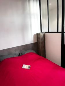 czerwone łóżko z książką na górze w obiekcie Studio tout équipé avec chambre indépendante w Aix-les-Bains