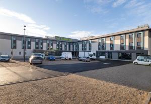 a large building with cars parked in a parking lot at B&B HOTEL Massieux Genay in Genay