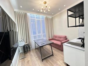 a living room with a pink couch and a table at MegaPark Appartments in Almaty