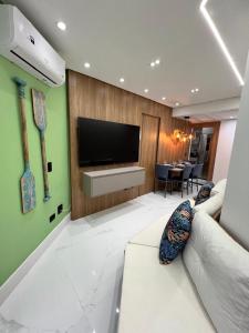 a living room with a television and a white couch at BARRAVENTO RESIDENCE - RIVIERA SÃO LOURENçO in Bertioga