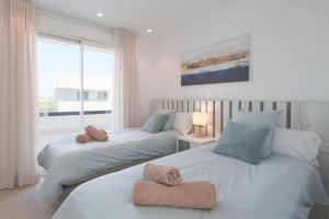 two beds with towels on them in a bedroom at Villa Almendro Santa Rosalia Lake and Life Resort by PREMIUM SPAIN PROPERTIES in Torre-Pacheco