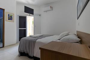 a white bedroom with a bed and a table at Casa com Piscina climatizada , Jacuzzi 4 Quartos. in Bertioga +16 photos