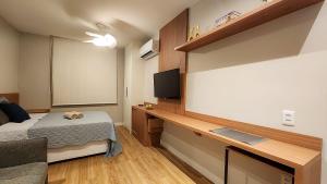a bedroom with a bed and a desk with a television at Em frente à praia - conforto, localização e vista in Rio de Janeiro