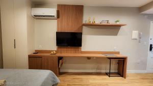 a room with a desk with a television on a wall at Em frente à praia - conforto, localização e vista in Rio de Janeiro