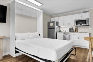 Un dormitorio blanco con una cama y una cocina. en Summer Sands - 108 by Sea Scape Properties, en Wrightsville Beach