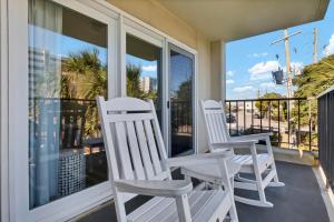 Dos sillas blancas sentadas en un porche con vistas al océano en Summer Sands - 108 by Sea Scape Properties, en Wrightsville Beach