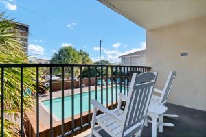 Un balcón con dos sillas y una piscina. en Summer Sands - 108 by Sea Scape Properties, en Wrightsville Beach 10 fotos más
