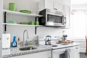 a white kitchen with a sink and a microwave at Suite One King Bed 2TVs Free Parking & museums in Richmond
