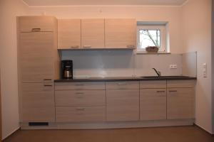 eine Küche mit Holzschränken und Spüle und einem Fenster in der Unterkunft Ferienwohnung an der Obermosel in Oberbillig