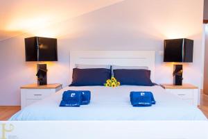 ein Schlafzimmer mit einem weißen Bett mit zwei blauen Taschen darauf in der Unterkunft Bleu Soleil By Ericeira Property in Mafra + 15 Fotos