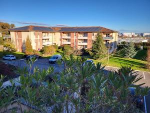 an apartment building with cars parked in a parking lot at Le Beluga XL - Confort et proximité Airbus in Colomiers