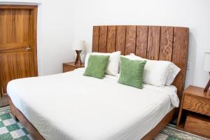 a bedroom with a large white bed with green pillows at Casa Monarcas - Victoria (with AC) in Guadalajara +23 photos