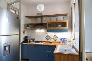 a kitchen with blue cabinets and a sink and a refrigerator at VillaThomas in Campofelice di Roccella
