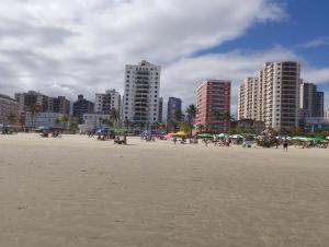 a group of people on a beach with umbrellas at Apto Domeni, seu conforto a 10 min da praia! in Praia Grande