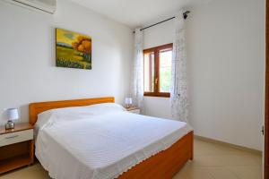 a white bedroom with a bed and a window at Casa Mariposa in Alghero
