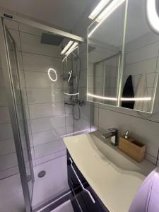 a bathroom with a sink and a shower with a mirror at Charmant appart, avec parking à quelques minutes du départ des télécabines in Crans-Montana