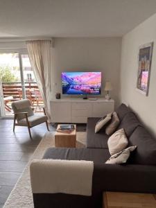 a living room with a couch and a flat screen tv at Charmant appart, avec parking à quelques minutes du départ des télécabines in Crans-Montana