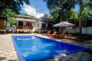 a pool with chairs and an umbrella next to a house at Edward's Bungalow in Tangalle