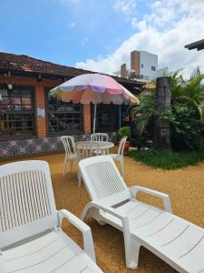 a group of white chairs and tables and an umbrella at Sunshine Residencial in Bombinhas +20 photos