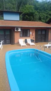 a large swimming pool with chairs and a house at Sunshine Residencial in Bombinhas