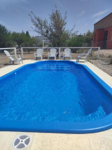 a blue swimming pool with chairs in a yard at Departamentos Atardecer Serrano in Arroyo de Los Patos