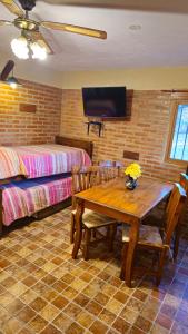 a room with a wooden table and a bed and a table and chairs at Departamentos Atardecer Serrano in Arroyo de Los Patos