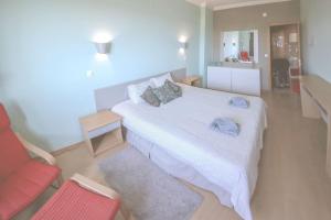 Un dormitorio con una cama blanca y una silla roja. en Ericeira Beach Tour, en Ericeira 20 fotos más