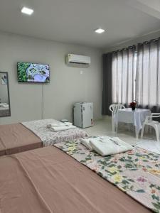 a hotel room with two beds and a table and a room at Apto. Aconchego familiar c/cozinha até 06 pessoas in Rio Branco