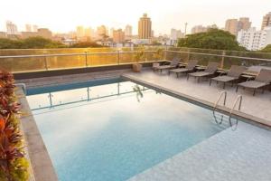 a swimming pool on top of a building with chairs at Village Iguassu Hotel in Foz do Iguaçu