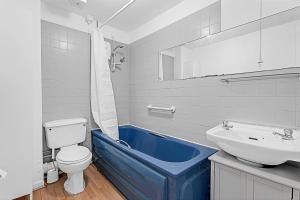 ein Badezimmer mit einer blauen Badewanne neben einer Toilette und einem Waschbecken in der Unterkunft Beautiful Three-Bedroom House in Richmond in Richmond upon Thames
