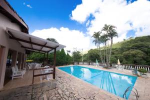 a pool at a resort with chairs and trees at Pousada Ypê das Montanhas in Monte Alegre do Sul