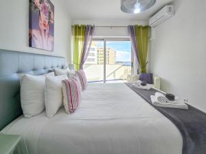 ein Schlafzimmer mit einem großen weißen Bett mit einem Fenster in der Unterkunft Apartment Concorde Sky Vista Mar in Portimão