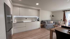 a kitchen with white cabinets and a living room at BPirineos-Llardana in Benasque