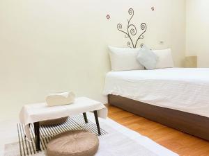 ein Schlafzimmer mit einem Bett, einem Hocker und einem Tisch in der Unterkunft 花蓮密絲朵包棟民宿 4-14人 l 近花蓮火車站 l 電動麻將桌 in Hualien
