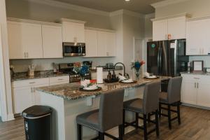 a kitchen with white cabinets and a island with bar chairs at Contractor Ready No Penalty Changes Fast Wi-F in Lake Charles